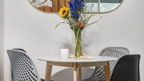 Ett matbord med en vas med blommor, ett ljus och en liten skål med nötter.