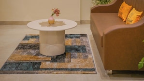Un salon avec un canapé marron, une table basse blanche et un grand tableau abstrait accroché au mur.