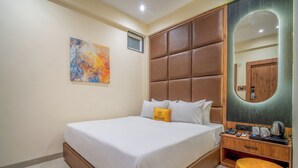 Une chambre d’hôtel avec un grand lit, une table de chevet avec une machine à café, un miroir et un tableau au mur.