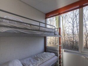 A dormitory room with bunk beds, a window with a view of trees, and a radiator. - 3-bedroom Countryside Stay in Simpelveld (Simpelveld)