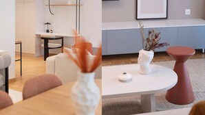 Moderni olohuone, jossa on pyöreä sohvapöytä, valkoinen maljakko kuivine kasveineen ja punainen, huomiota herättävä jakkara.