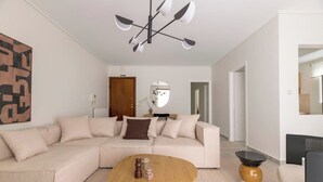 A modern living room with a beige sectional sofa, a wooden coffee table, and a black and white floor lamp. - Marousi 2BR Prestige Apartment (Marousi)