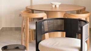 A dining area with a round wooden table, two chairs, and a small round table with a bowl. - Marousi 2BR Prestige Apartment (Marousi)