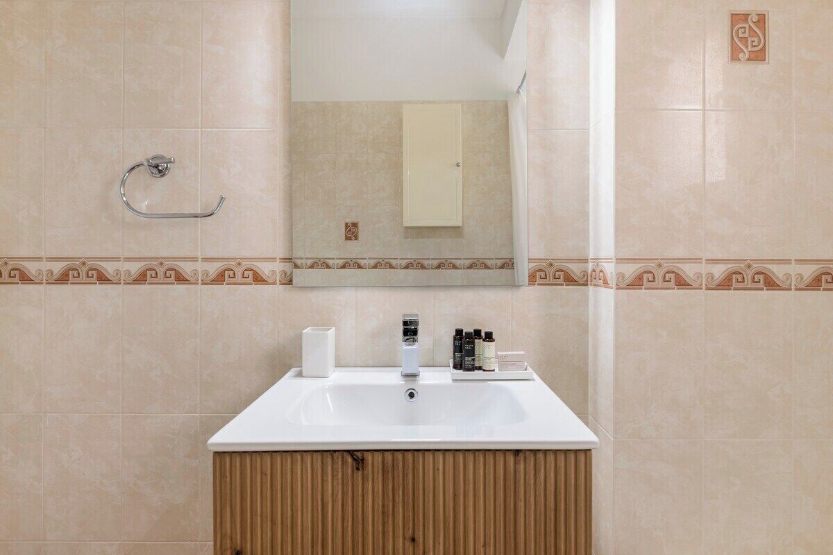 A bathroom with a white sink, a mirror, and a towel rack.