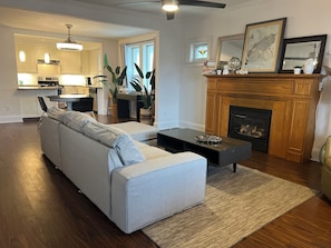 A living room with a sofa, coffee table, fireplace, and a dining area with chairs and a table.