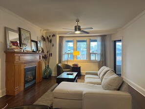 A living room with a fireplace, a sofa, a coffee table, a chair, and a window with curtains.