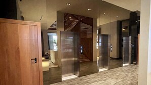 Un vestíbulo moderno con una puerta de madera, un mostrador de recepción y una escalera que sube a un piso superior.