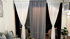 Una sala de estar moderna con un sofá, una mesa de centro y vistas a través de ventanas grandes con cortinas.