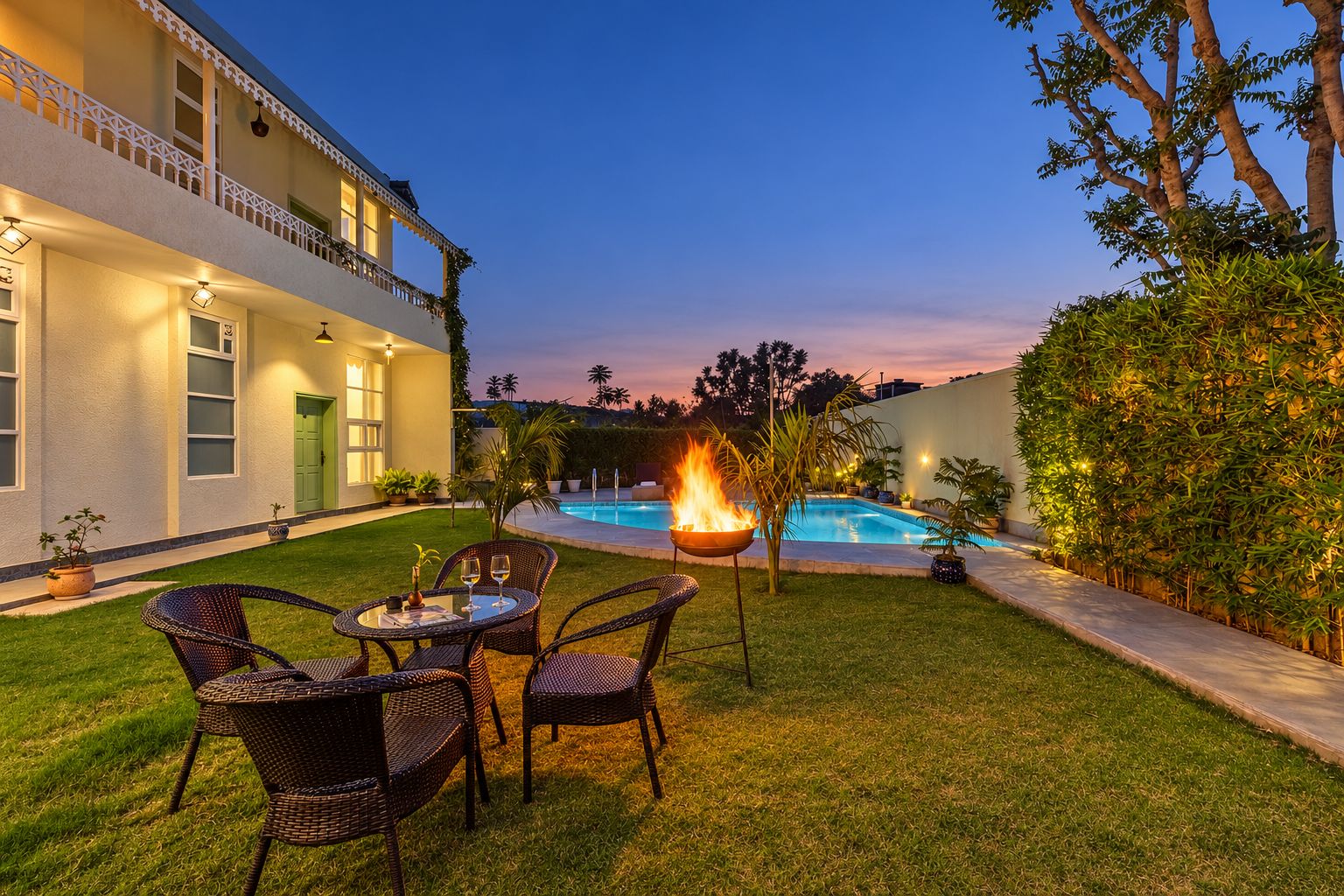 A poolside area with a fire feature, outdoor seating, and a building with a balcony.