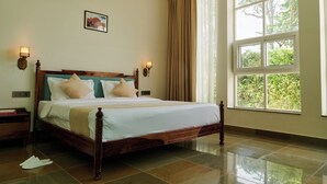A neatly made bed with a wooden frame, two bedside tables with lamps, and a large window with curtains. - Free Birds Boutique Stay Amer, Jaipur (Amer)