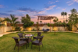 A patio with wicker furniture, a hanging chair, and a table with drinks. - Free Birds Boutique Stay Amer, Jaipur (Amer)