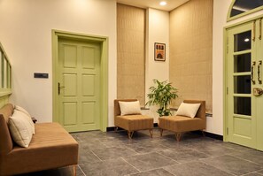 A reception area with a green door, two armchairs, a potted plant, and a brown sofa. - Free Birds Boutique Stay Amer, Jaipur (Amer)