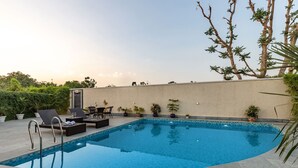 A swimming pool with lounge chairs and tables, surrounded by potted plants and trees. - Free Birds Boutique Stay Amer, Jaipur (Amer)