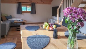 Ein gemütliches Wohnzimmer mit einer Couch, einem Couchtisch und einem Essbereich mit Blumen und Früchten.