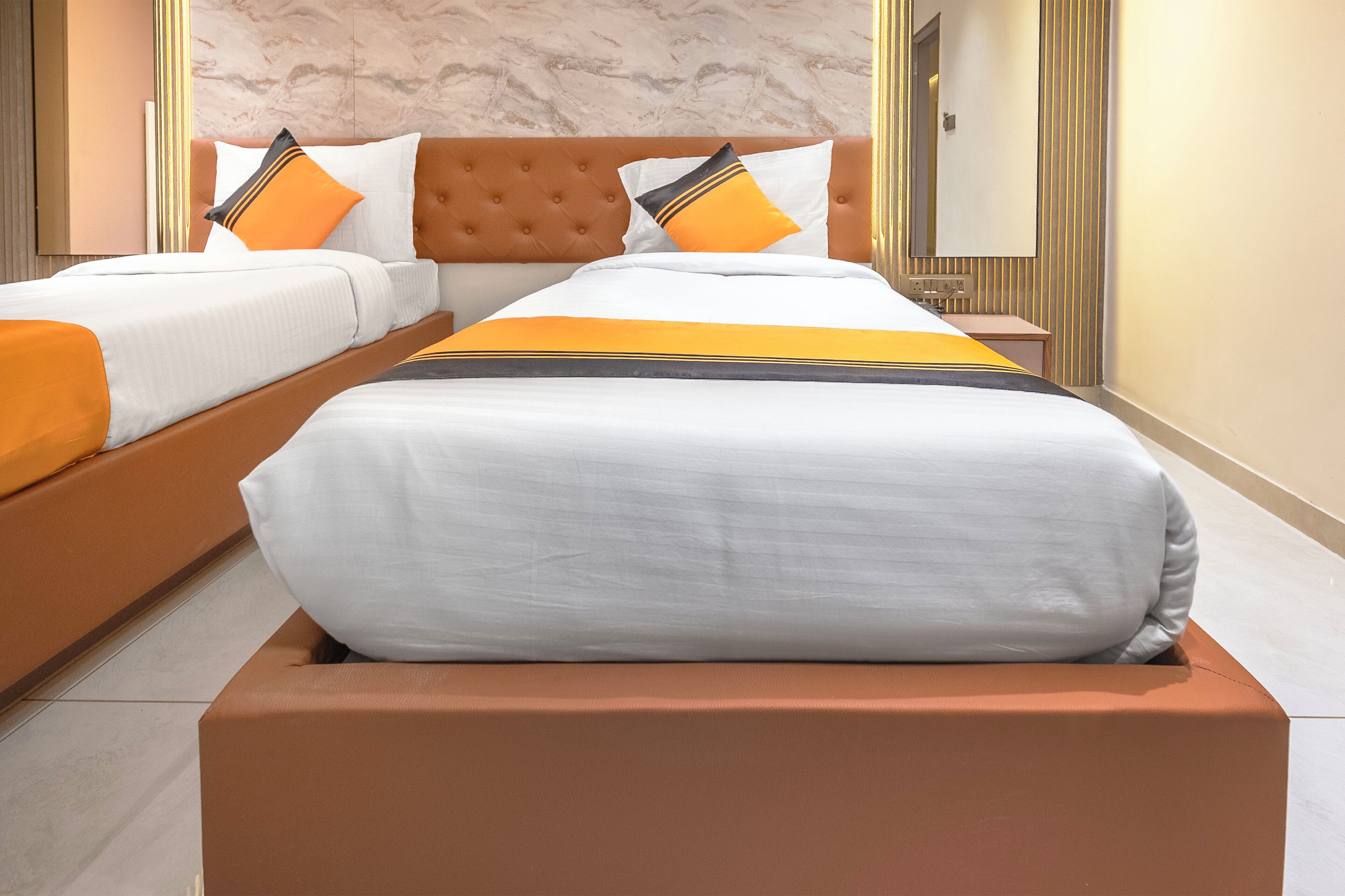 A hotel room with a large bed, a nightstand, and a mirror.