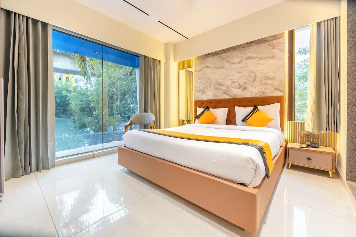 Un hotel moderno con una cama grande, una mesita de noche, una silla y vistas a zonas verdes por la ventana.