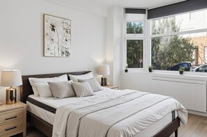 Un dormitorio con una cama grande, lámparas de noche, una ventana con vistas y un radiador.