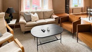 En stue med en beige sofa, et rundt sofabord og en træstol.