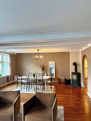 A spacious living room with a dining area, a fireplace, and a large mirror.