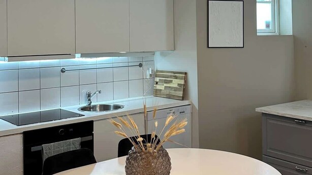 Una cocina moderna con armarios blancos, una mesa de comedor redonda y sillas negras.