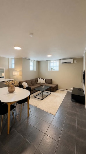 Een moderne woonkamer met een bank, salontafel en een eethoek.