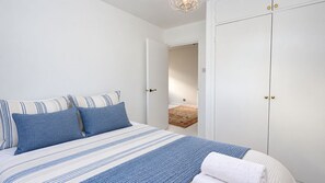 Une chambre à coucher avec un lit, des oreillers, une couverture et une porte donnant sur une autre pièce.