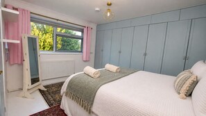Une chambre à coucher avec un lit, une fenêtre avec des rideaux, un radiateur et un luminaire au plafond.