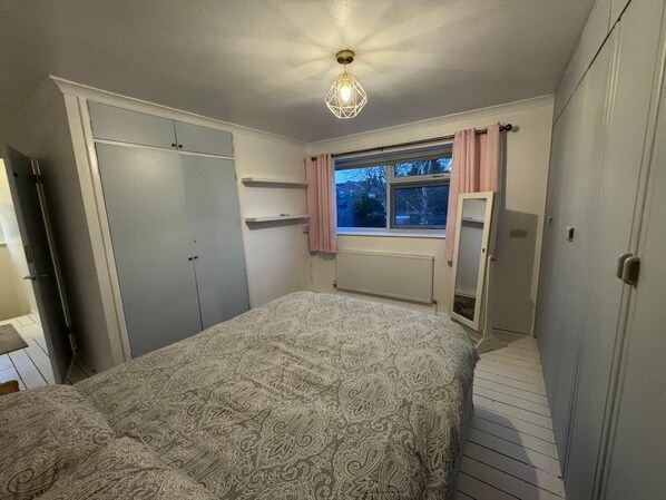 A bedroom with a bed, wardrobe, and a window with curtains.