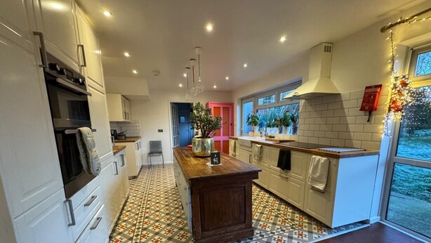 Een moderne keuken met witte kasten, een houten eiland en een vloer met een patroon.