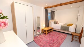 Une chambre à coucher comprenant un lit, une table de chevet, une chaise, une armoire et un miroir.
