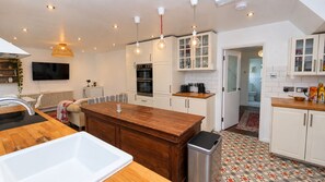 Une cuisine moderne avec des meubles blancs, un îlot central en bois et un sol carrelé.