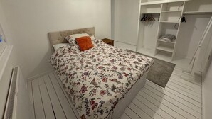 Een slaapkamer met een bed, een kledingkast en een hanglamp.