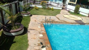 A swimming pool with a stone deck, surrounded by grass and potted plants. - Aldi Jambo Hotel (Homa Bay)