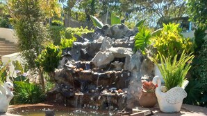 Ein Garten mit einem Felsenwasserfall, einer Schwanstatue und einer Krokodilstatue.