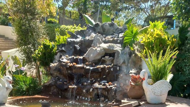 A garden with a rock waterfall, a swan statue, and a crocodile statue. - Aldi Jambo Hotel (Homa Bay)