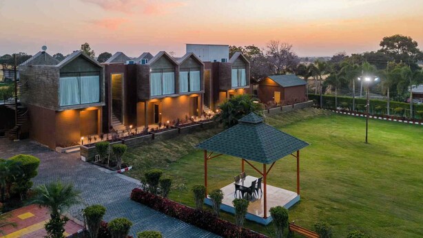 A modern hotel with multiple units, a well-maintained lawn, and a gazebo. - Eco Holiday Resorts (Indore)