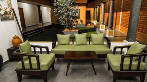 A seating area with a sofa and chairs, a small table, and a potted plant. - Vaigayi Ayurvedic Resort (Kunnathunad)