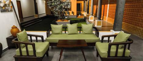Eine Sitzecke mit einer Couch und Sesseln, einem kleinen Tisch und einer Topfpflanze.