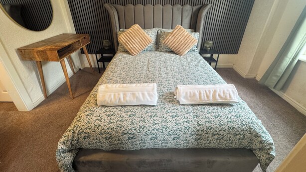 A neatly made bed with a floral bedspread, two pillows, and two folded towels. - Reads Avenue - Next To HA Social Club - Winter Gardens and Town Centre! (Blackpool)