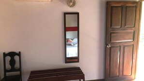 Une pièce avec un banc en bois, un miroir et une porte.