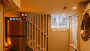 Ein Waschraum mit Waschmaschine, Kühlschrank und einer Treppe zu einer weiteren Ebene.
