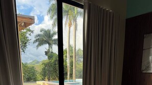 Ein Zimmer mit Bett, großen Fenstern und Blick auf Palmen und einen Pool.
