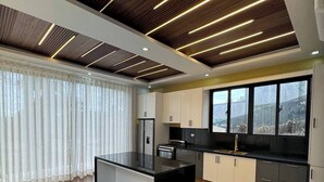 Eine moderne Küche mit einer zentralen Kochinsel, Holzboden und einer Decke mit linearer Beleuchtung.