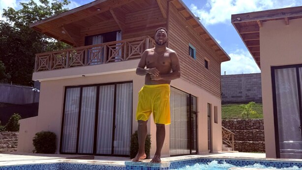 Eine Person steht am Poolrand, im Hintergrund ein modernes Haus.