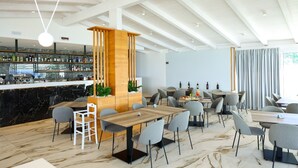 Un restaurant moderne doté d’un bar, d’un sol en marbre et d’un plafond haut avec des poutres apparentes.