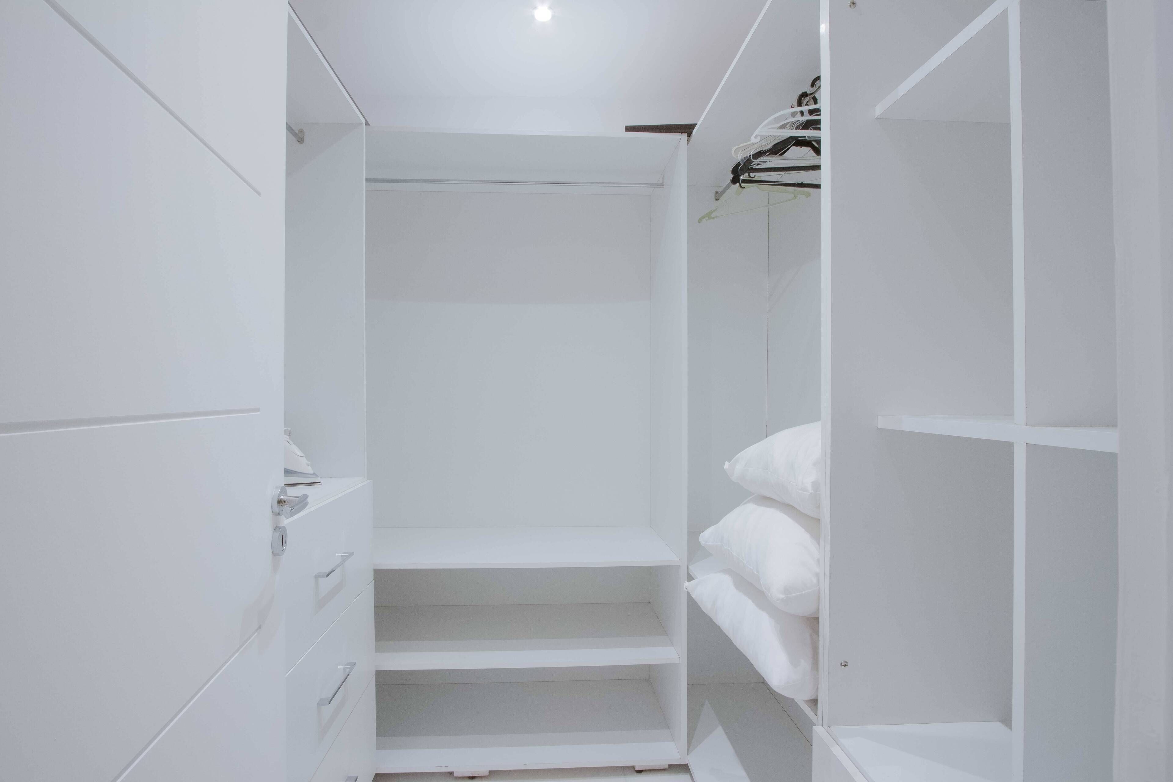 A white walk-in closet with shelves and hanging space.
