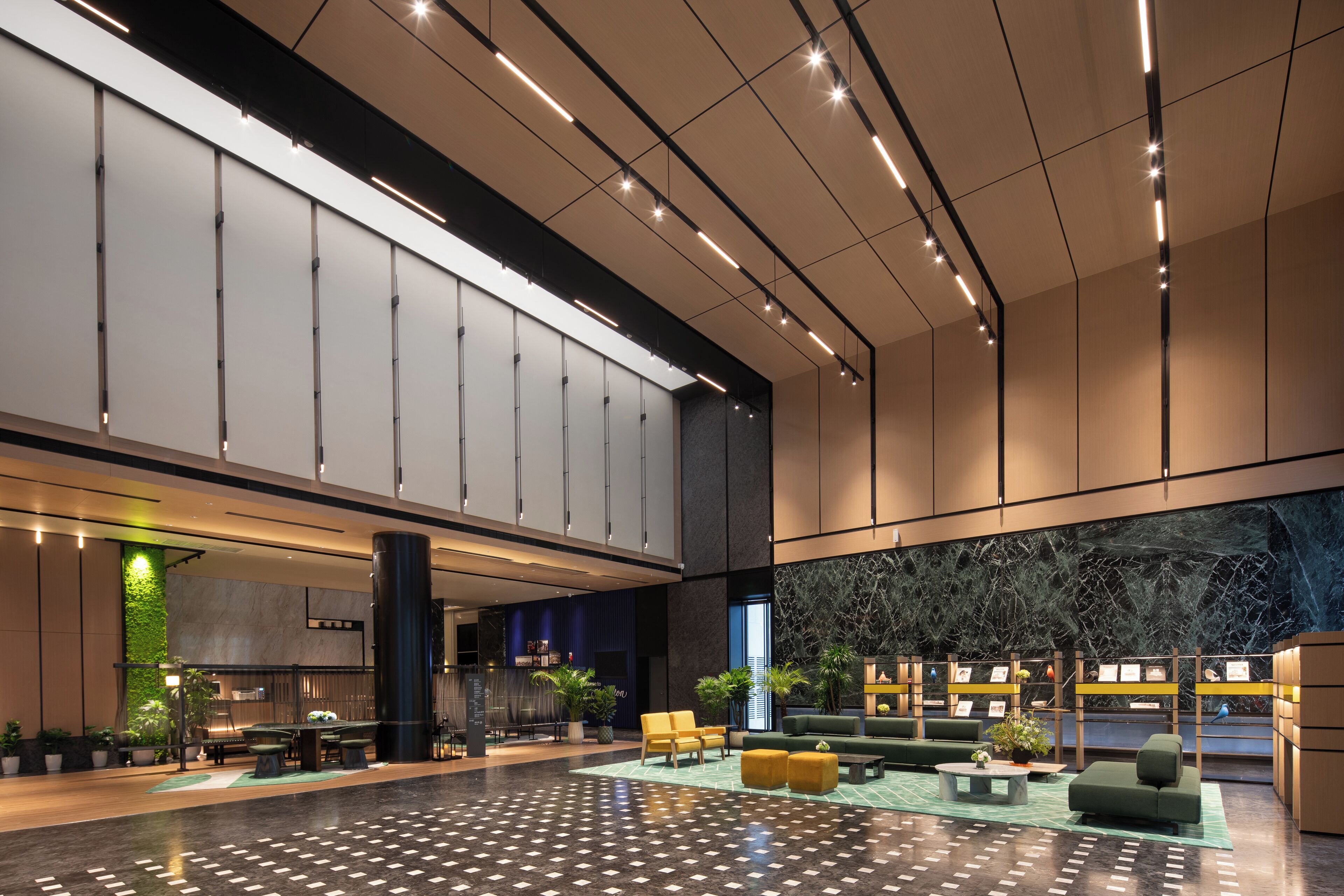 Eine geräumige Lobby mit hoher Decke, moderner Beleuchtung und Sitzbereichen.