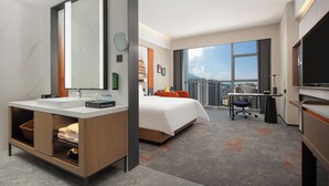 Hotelkamer met een groot bed, een bureau, een televisie en een badkamer met een grote spiegel en wastafel.