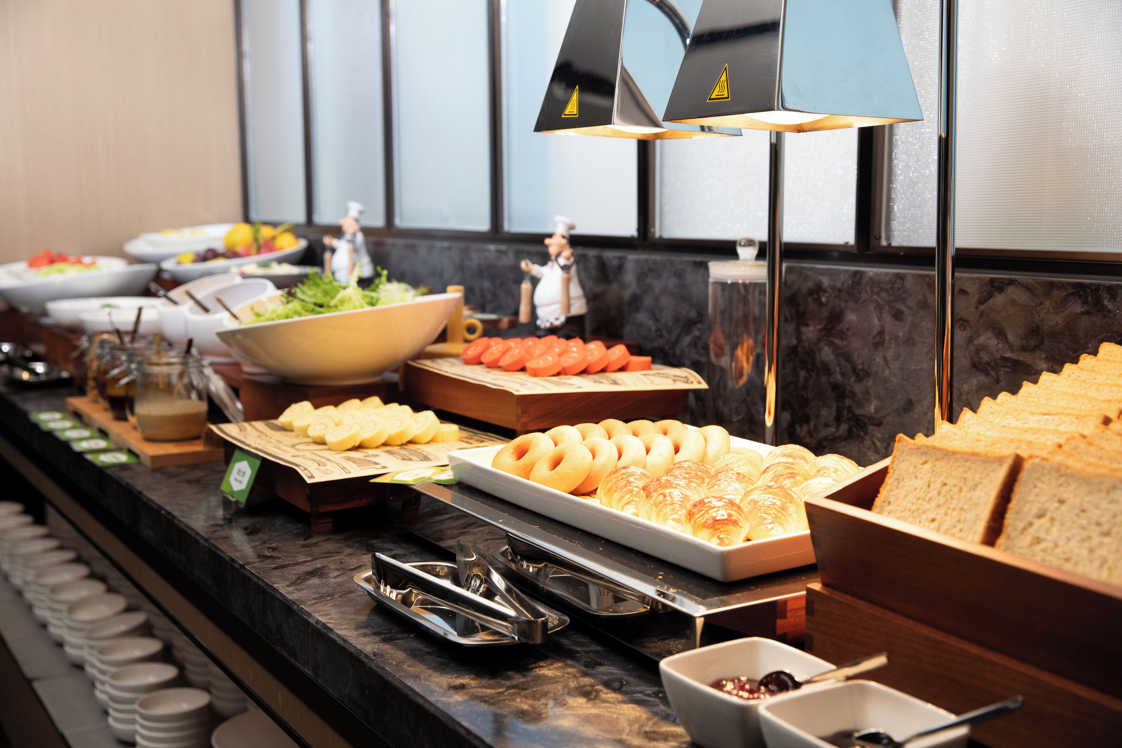 Ein Buffet mit verschiedenen Speisen, darunter Salate, Früchte und Brot.