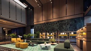 Een ruime lobby met zitgedeeltes, een marmeren wand en een goed verlichte receptiebalie.